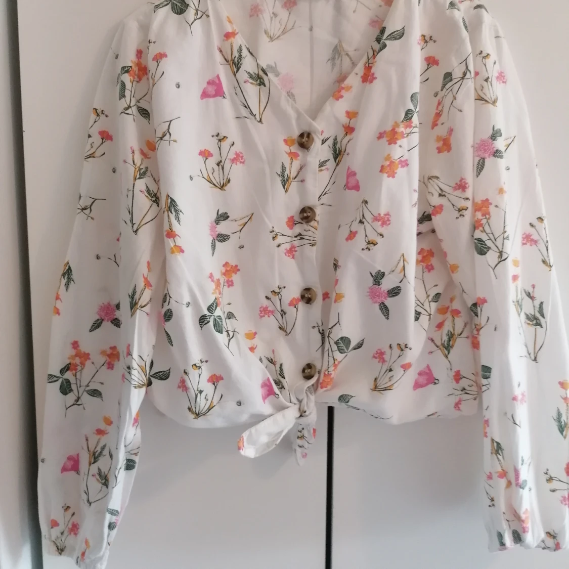 Vit blommig blus med knyt och knappar