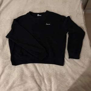 Svart sweatshirt med broderad text - Svart sweatshirt från H&M med vit broderad text 'love' på bröstet. Klassisk rund halsringning och långa ärmar. Tillverkad i mjuk bomullsmix som är skön att ha på sig. Perfekt för en chill och stilren look.