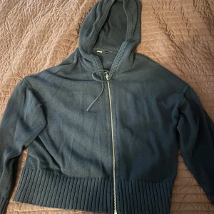 Mörkblå stickad hoodie med dragkedja - Säljer en mörkblå stickad hoodie från Bik Bok med hel dragkedja framtill och snörning vid huvan. Tröjan har långa ärmar och bred ribbad kant nedtill som ger en schysst look. Perfekt för dig som gillar chill och stilren design.