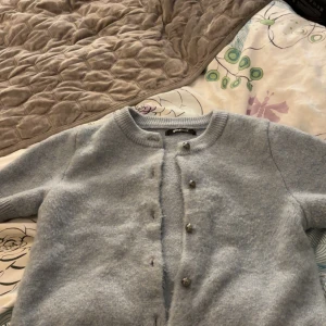 Ljusgrå kofta från Gina Tricot XS - Supermjuk ljusgrå kofta från Gina Tricot i storlek XS. Klassisk rund halsringning, långa ärmar och snygga knappar framtill. Perfekt att slänga över en topp när det är kyligt. 