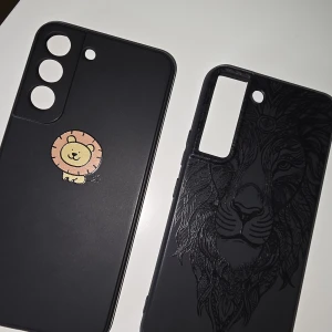 Samsung Galaxy S22 Skal - Två snygga mobilskal för Samsung Galaxy S22. Ett med söt lejon-illustration och ett med elegant lejonmönster. Båda i svart, i fint skick utan synligt slitage. 