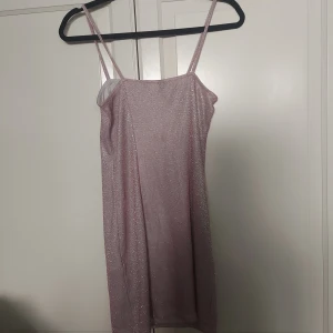 Glittrig rosa/lavendel färgad klänning DIVIDED - ⚠️Skriv till mig innan köp!⚠️                                            Säljer en snygg kort klänning från DIVIDED i storlek S. Klänningen är lavendel färgad med glittrigt tyg, smala axelband och en liten slits nedtill. Perfekt för dig som vill sticka ut med en glammig look. Materialet är mjukt och följsamt syntet. 