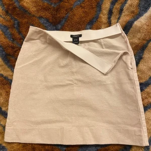 Beige manchesterkjol - Beige kortkjol i manchester. Kjolen har en rak passform och är av velurmaterial. Perfekt att matcha med stickade tröjor eller en snygg topp. Enkel och stilren design med bred linning.