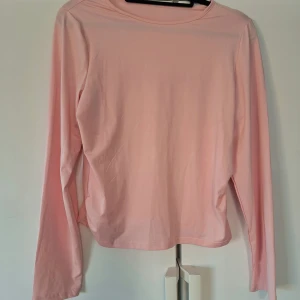 Ljusrosa långärmad tröja - Enkel och stilren ljusrosa långärmad tröja i mjuk bomull. Tröjan har rund halsringning och en rak passform som passar perfekt till jeans eller kjol. Perfekt basplagg för garderoben. Aldrig använd. Som M/L