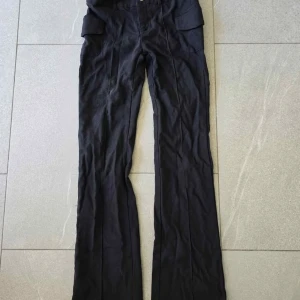 Svarta cargopants med raka ben - Svarta cargopants med raka ben och stora fickor på sidorna. Byxorna har en klassisk passform och är perfekta för en avslappnad streetstil. Tillverkade i ett mjukt material som känns bekvämt hela dagen.