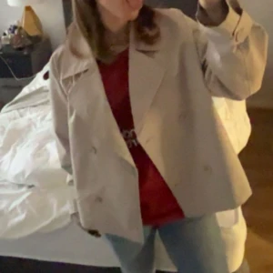 Beige trenchcoat  - Säljer en beige trenchcoat med dubbelknäppning och breda slag. Jackan har en klassisk look och är perfekt att slänga över en hoodie eller t-shirt. Från lager 157 köpt i storlek L för att få den mera oversize modellen, skulle säga att den är som s/m