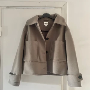 Grå/Beige kort kappa från Kappahl XS - Stilren och snygg grå/beige jacka från Kappahl i storlek xs. Endast använd ett par gånger och i jättefint skick. Inte nopprig alls💕