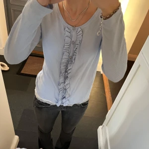 Blå stickad kofta  - Blå kofta med volanger från Ashley Brooks i storlek 38, skulle säga att den passar S och M. Fint skick. Använd gärna köp nu!