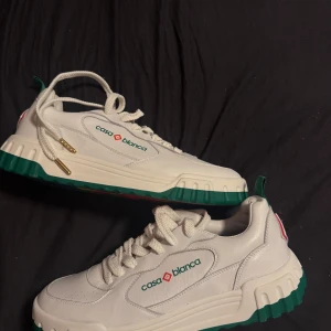 Casa Blanca vita sneakers i skinn - Säljer ett par Casablanca court logo skor i färgen grön. Helt oanvända och är helt nya, säljer då de är fel storlek och ej passar mig. Köpta på miinto för 3100kr och säljer för 2750kr. Skriv för fler bilder eller frågor. Kvitto finns! LÅDAN ÄR KASTAD!!! FINNS BARA DUSTBAG!!! PRIS KAN DISKUTERAS!!!