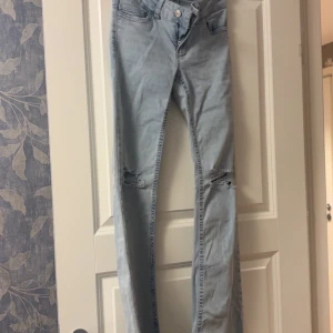 Ljusblå bootcut jeans  - Säljer ett par ljusblå jeans med bootcut-modell och hål vid knäna. Men låg midja och är från nelly.
