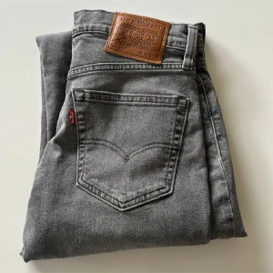 Grå Levis 511 jeans straight fit - Snygga grå Levis 511 jeans med klassisk femficksdesign och läderpatch bak. Jeansen har en rak passform och är tillverkade i mjukt denimtyg. Perfekta för dig som gillar en stilren look med en modern touch.