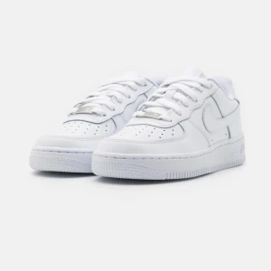 Nike Air Force 1 vita sneakers - Klassiska Nike Air Force 1 sneakers i helvitt skinn med perforerad tå, rund tå och platt sula. Skorna har snörning och diskret Nike-logga på sidan och hälen. Perfekta för dig som vill ha en clean och tidlös look till vardags. De är använda.