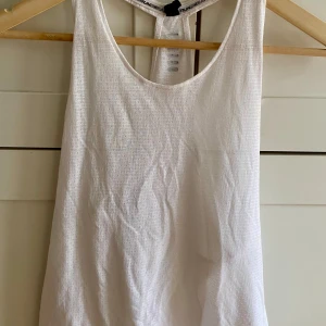 Vit linnetopp från Under Armour - Säljer en vit linnetopp från Under Armour som är superskön att träna i!