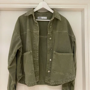 Zara jacka  - Säljer en snygg grön jacka från Zara med stora fickor framtill. Jackan har knappar längs hela framsidan. 