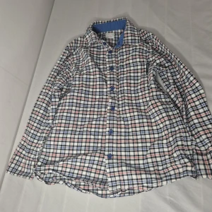 Rutig skjorta från Polarn O. Pyret - Riktigt snygg rutig skjorta från Polarn O. Pyret i vitt, blått och rött. Skjortan har blå knappar och klassisk krage med blå insida. Perfekt för dig som gillar en avslappnad men ändå stilren look.