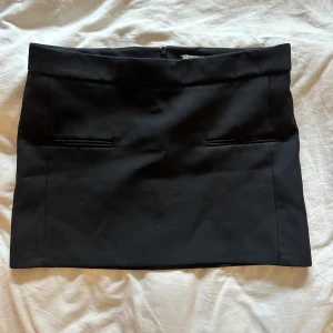 Svart mknikjol från Zara - Säljer min svarta minikjol från Zara med rak passform och fickdetaljer framtill. Kjolen har dold dragkedja bak och är tillverkad i ett slätt tyg som ger en clean look. Perfekt att matcha med en crop top eller oversized tröja.💞😍