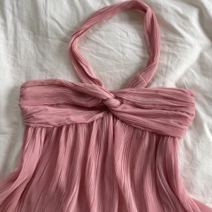 Fin Rosa halterneck från Zara - Supersöt rosa plisserad top från Zara med halterneck och knutdetalj framtill. Lätt och flowigt tyg. Den säljs inte längre på Zara och jag säljer den då den inte kommer till användning. Har inga defekter förutom en lite brun fläck som knappt syns.  I storlek S.