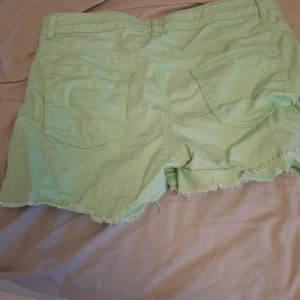 Mintgröna shorts från Name It - Snygga mintgröna shorts från Name It i jeansmaterial. De har fransig kant nertill, klassisk femficksdesign och dragkedja med knapp framtill. Perfekta för sommaren och ger en fräsch vibe till din outfit. Och igga mina fötter😭jätte bra skick 