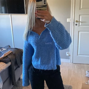 Blå stickad tröja från Gina Tricot - Mysig blå stickad tröja från Gina Tricot med v-ringad hals och lite loose passform. Tröjan har långa ärmar och ribbad struktur som ger en cool och avslappnad vibe. Perfekt att slänga på sig när det är lite kyligt ute.💙