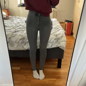 Grå skinny jeans från Lager 157 - Säljer ett par gråa skinny jeans från Lager 157 med hög midja och klassisk femficksdesign. Jeansen är i stretchigt bomullsmaterial och sitter tight hela vägen ner. (Använt fåtal gånger) 