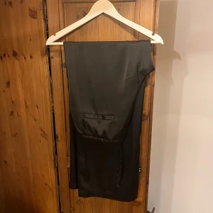 Svarta vida byxor i satinlook - Snygga svarta byxor med rak och vid passform i glansigt satinliknande material 🙌🏻🙌🏻 Strl M men sitter mer som en L, använt enstaka gånger 