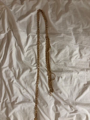 Guldfärgat skärp - Säljer ett chunky guldfärgat skärp som passar perfekt som accessoar. Kedjan har stora länkar och en rund bricka vid låset. Ger en cool och trendig look till din outfit.