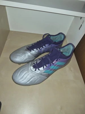 Adidas Copa Sense "Champions Code"  Storlek 44 - Säljer ett par riktigt schyssta adidas Copa Sense i den unika färgkombinationen "Champions Code" (Silver/Lila/Mint). ​Skorna är precis genomgångna och grundligt rengjorda för hand, så de är fräscha och redo för planen direkt! ​Om skorna: ​Modell: Adidas Copa Sense. ​Färg: Silver med detaljer i lila och mintgrönt. ​Skick: Mycket fint begagnat skick. De har blivit väl omhändertagna och materialet är fortfarande mjukt och följsamt. ​Storlek 44