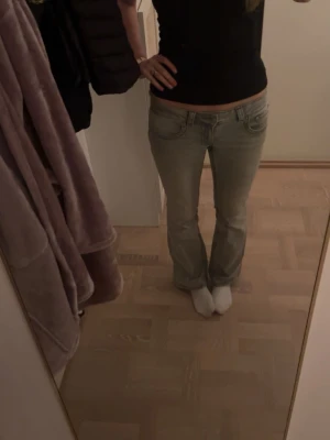 Grå bootcut low waist jeans - Säljer ett par gråa jeans från Gina Tricot (Perfect Jeans) i storlek 38. De har låg midja, bootcut-ben och snygga detaljer med ficklock och knapp bak. Jeansen är i klassisk denim med en tvättad look.