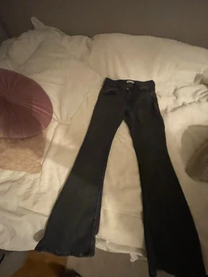 Svarta bootcut jeans från Perfect Jeans - Säljer ett par svarta bootcut jeans från Perfect Jeans i storlek 38. Jeansen har klassisk femficksdesign, hög midja och är tillverkade i ett stretchigt jeansmaterial. Perfekta för dig som gillar en snygg siluett med utsvängda ben. De har slitage längst ner på jeansen så de är fransiga.