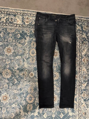 Slim Glenn svarta skinny jeans - Svarta skinny jeans från Slim Glenn med slitningar och snyggt tvättad look. Jeansen har fem fickor, knappgylf och smal passform som sitter tajt längs benen. Perfekta för dig som gillar en modern och stilren vibe.