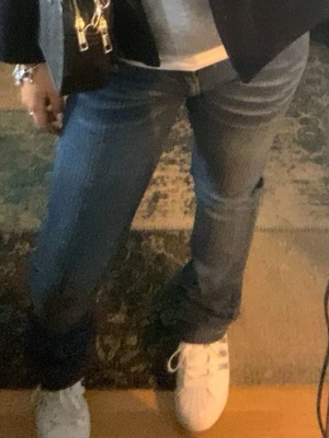  blå bootcut jeans - Säljer ett par klassiska jeans i blå tvätt. De har låg midja och bootcut-ben, vilket ger en snygg siluett. Jeansen är gjorda i slitstarkt denim och Perfekta för dig som gillar en tidlös och avslappnad look.