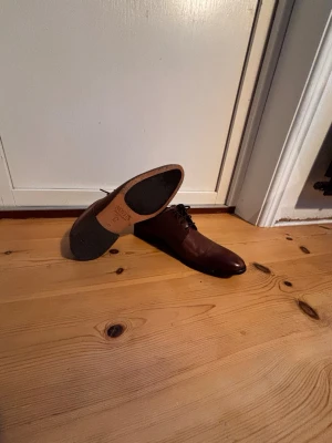 Bruna skinnloafers från Novita - Snygga bruna loafers från Novita i äkta skinn med klassisk snörning och rund tå. Skorna har en stilren design och svart sula, perfekta för dig som vill ha en dressad look. Passar till både jeans och kostym.