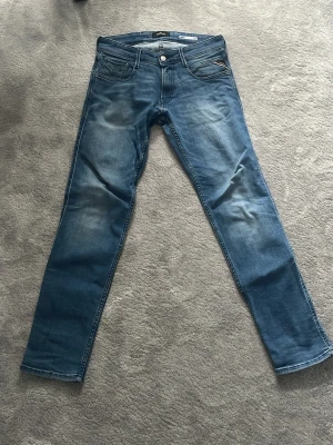 Replay Anbass Slim Fit Jeans Blå 30/30 - Säljer ett par Replay Anbass slim fit jeans i klassisk blå tvätt. Jeansen har fem fickor, snygga slitningar och Replay-logga på myntfickan. Tillverkade i stretchig bomullsdenim för skön passform. Pris är ej  hugget i sten. Tveka inte att ställa frågor!