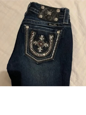 Miss Me mörkblå bootcut jeans - Snygga mörkblå Miss Me jeans med snygga detaljer i strl W26. Byxorna har låg midja och är bootcut med coola detaljer på fickorna 💕 Midja: 34, innerben: 82.