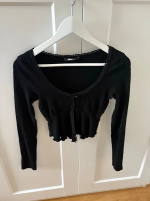 Topp - Långärmad svart tajt topp med slits i fram och rosett från Gina tricot i storlek xs