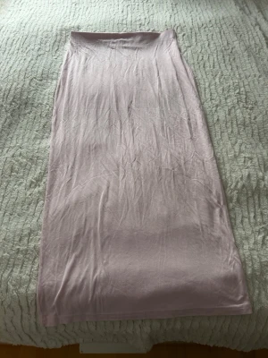 Ljusrosa långkjol från 157 - Säljer en enkel och stilren ljusrosa långkjol från 157. Kjolen har rak passform och är gjord i mjuk bomull som känns skön mot huden. Perfekt att styla med en crop top eller hoodie för en chill look.