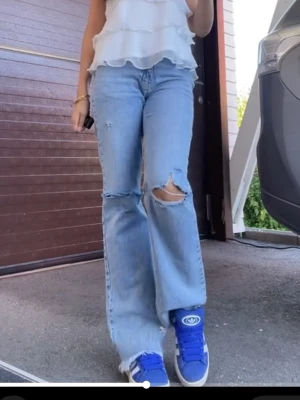 Ljusblå jeans  - Säljer ett par ljusblå jeans med slitningar på båda knäna. 