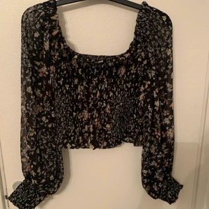 Blommig topp - Toppmed neddragna axlar. St: 44. Aldrig använd 