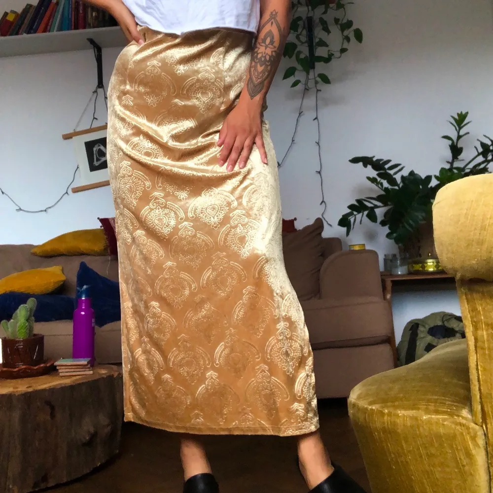 Lång guldig kjol i plysch material med mönster. Köpt i vintagebutik. Står att den är storlek 42/44 men skulle säga att den sitter som en M 😊 möts upp i Malmö, annars står köparen för frakt ✨. Kjolar.