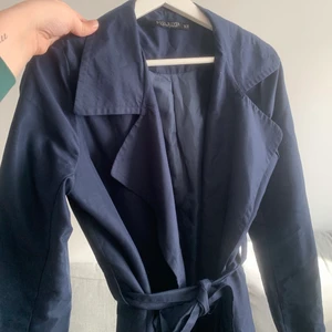 Mörkblå trenchcoat - Mörkblå Trenchcoat med band i midjan. Storlek XS. Fint skick. Kan mötas eller skickas med Postnord skicka lätt.