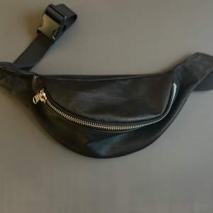 Black vegan leather. Large inner pocket, adjustable strap.