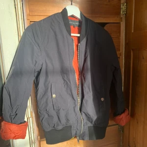 Bomber Jacka  - Svart bomber jacka med oranget innerfoder. Minns inte vart jag köpte den, inköpt för ca 2 år sedan, inga synliga skador/märken. två fickor med knäppning.                                                                        