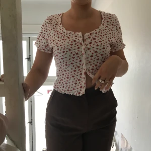 Söt blommig tröja med knappar - Supersöt cardigan-T-shirt med blommigt mönster. Supermjukt material!! Uppknäppbara knappar, superfin med linne under eller liknande. Vet ej storlek men ganska generös (modell på bilden bär vanligtvis S-M)