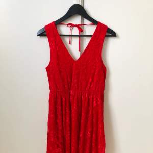 Röd knälång klänning i spets med djup rygg från Jeane Blush.