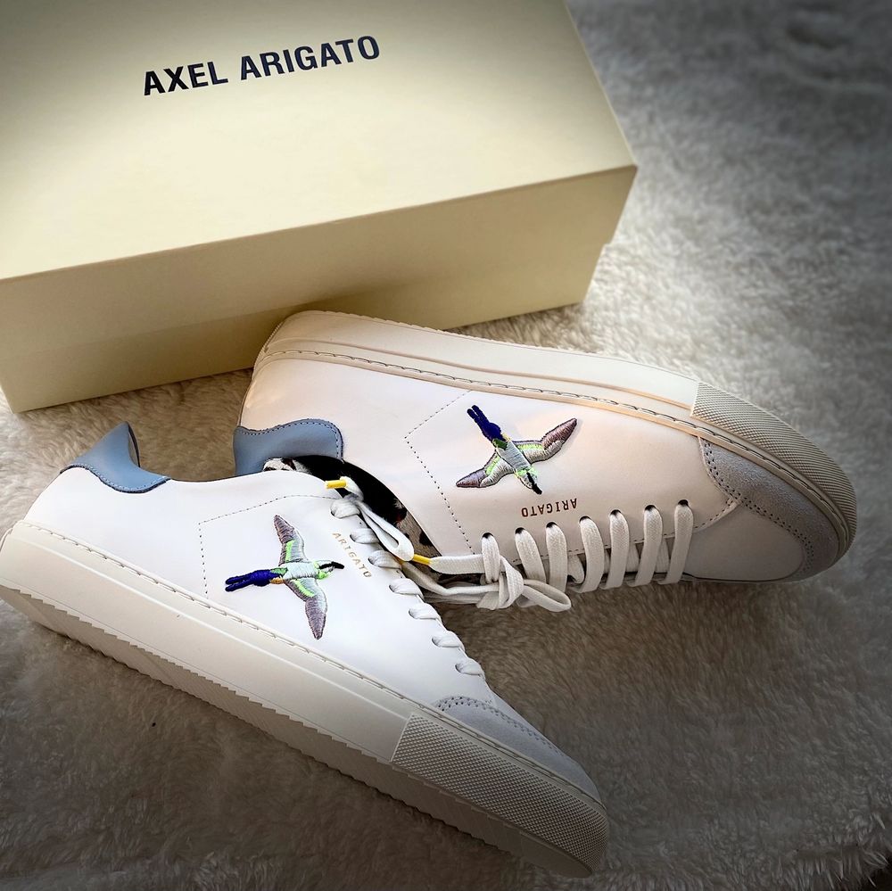 Oanvänd sneakers ”Axel Arigato ”, vit sneaker med övre läder.Prislapp på ,ingår även en väska till skorna.. Skor.