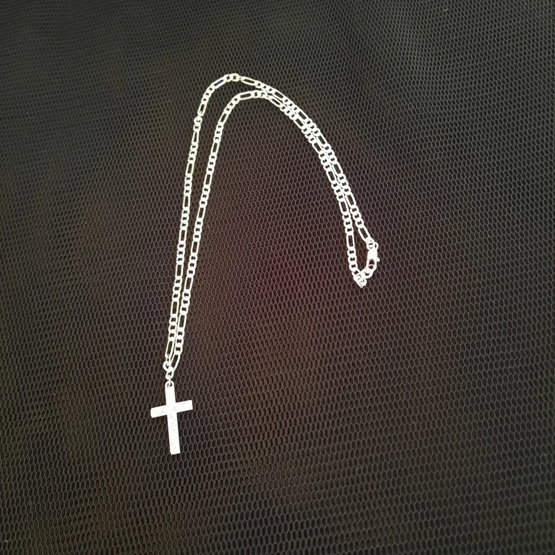 Silverfärgat kors på annorlunda kedja