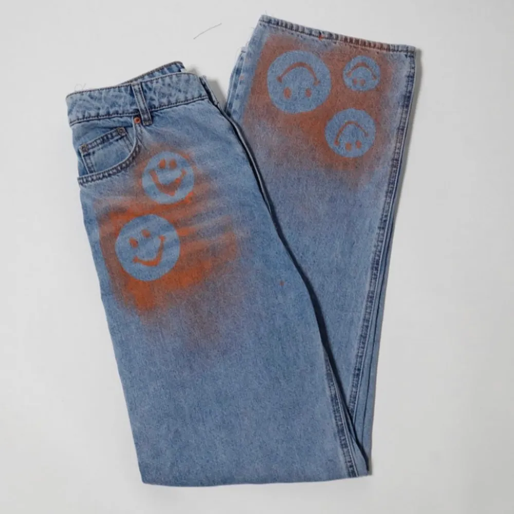 Högmidjade jeans i rak och lös fit. Oranga detaljer i ”smiley”motiv på byxbenet och vid fickan. Ursprungligen H&M jeans som är omgjorda av Scannable UF. Genom att skanna en QR-kod som finns fäst på plagget kan du läsa mer om materialet och dess miljöpåverkan!. Jeans & Byxor.