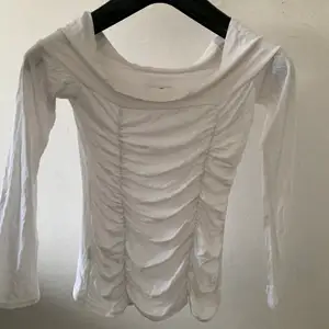 En fin vit topp med fin detalj på framsidan som går att använda som off the shoulder och som en vanlig tröja som täcker axlarna