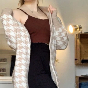 Kofta strl s - Kofta strl s, houndtooth mönstrad i vitt och beiget, går ungefär till knäna på mig som är 166cm, super fin under kappor eller bara för att dra över outfiten för att hålla värmen en sommar kväll, köparen står för frakten