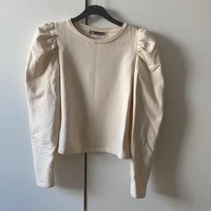 En sweatshirt med puffaxlar - En beige sweatshirt som aldrig är använd då den är för liten! Frakt tillkommer 